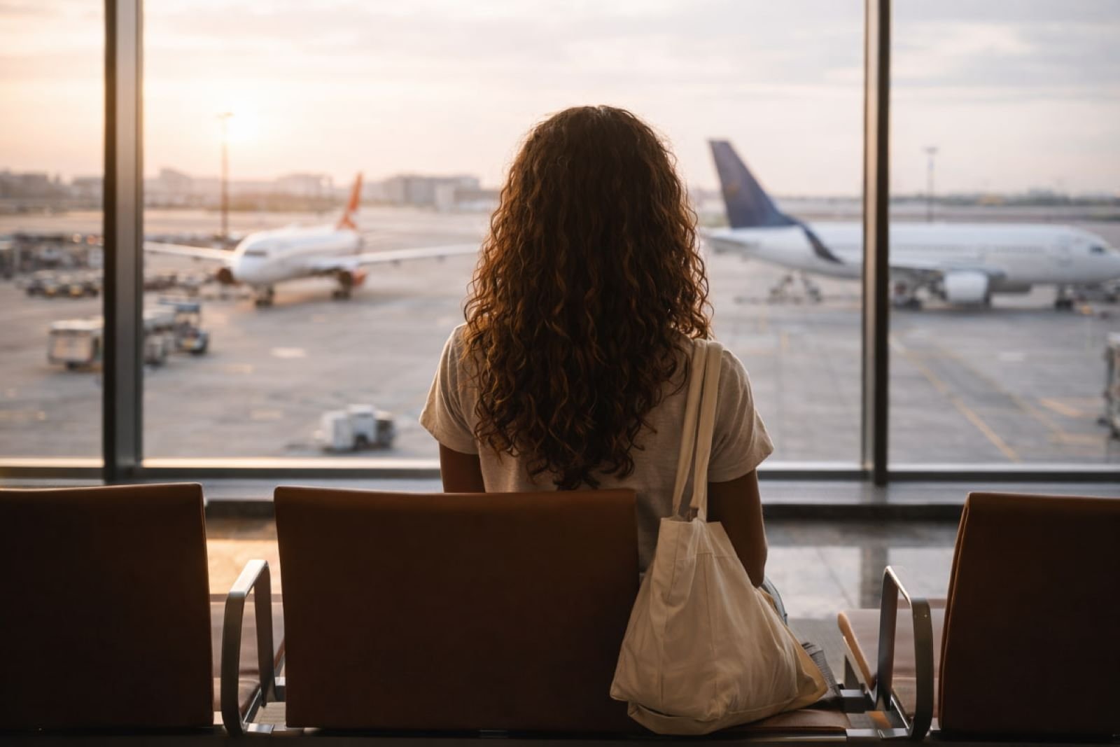 Black woman sitting alone at the airport watching planes during solo travel for Black women