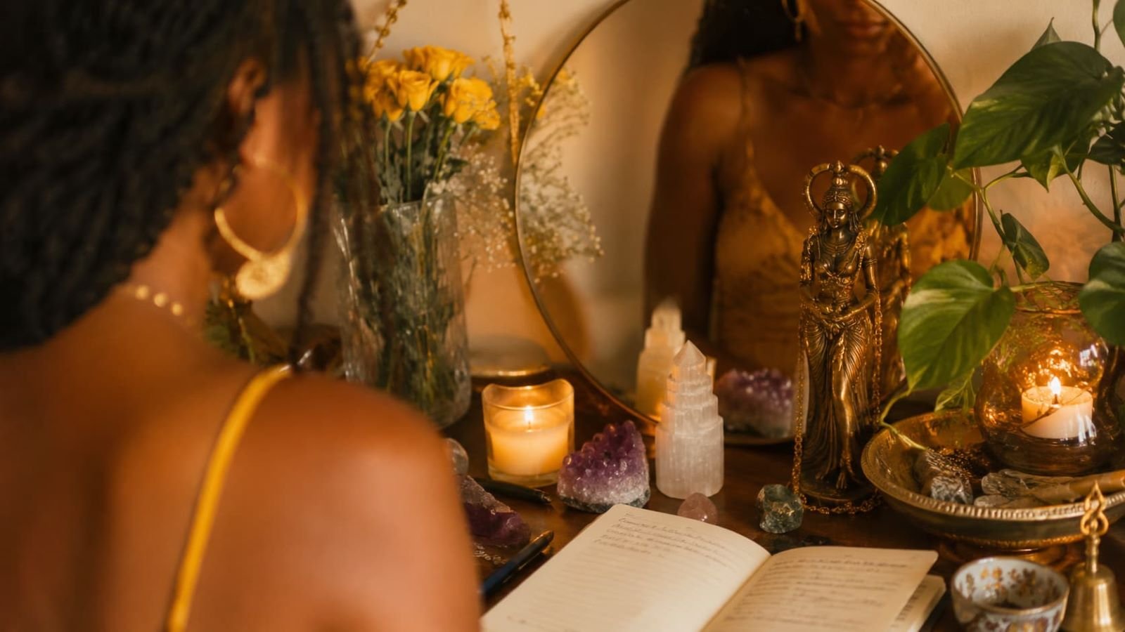 Black woman journaling at a candlelit altar with crystals and sacred objects, representing intuition, and feminine healing.
